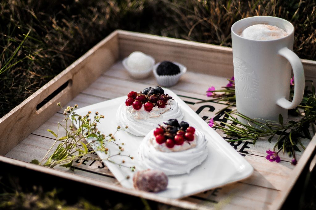 Hygge moment with wooden tray with meringue tarts and a cappuccino