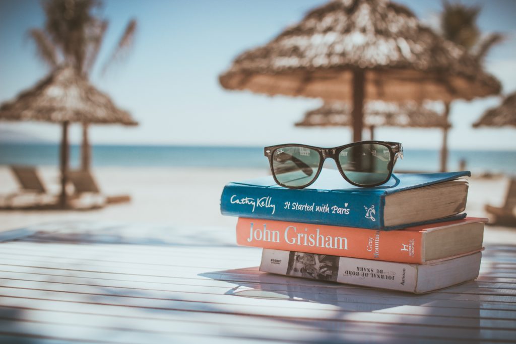 a pile of books on a table at the beach