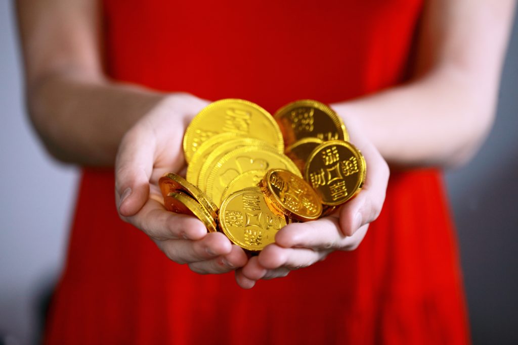 a woman holding big gold coins