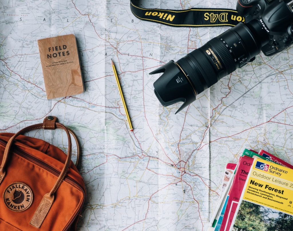 a map with a backpack, notebook, camera and guide books