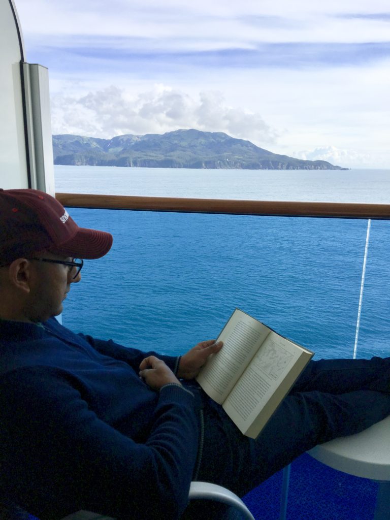 Prash enjoying a book and the Alaskan scenery from our private balcony on the Star Princess