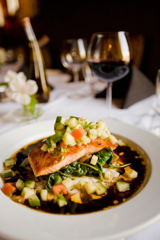 salmon dish and a glass of red wine at a restaurant