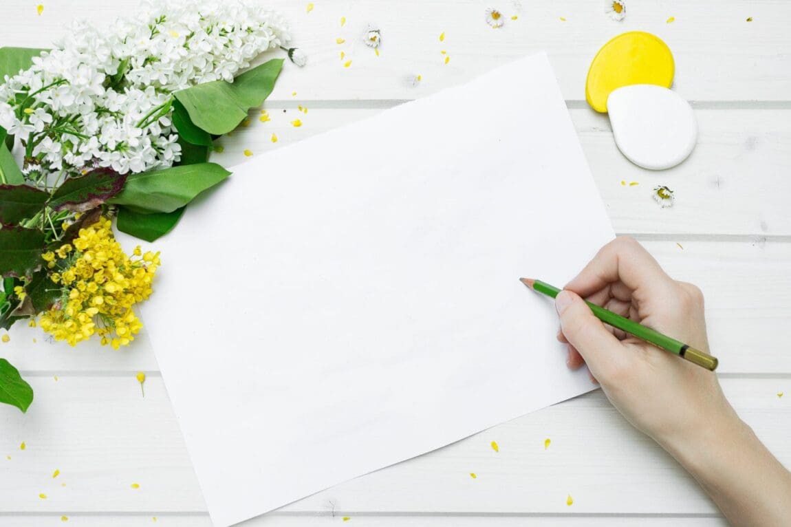 spring refresh, flatlay of a woman journaling with colorful flowers on the desk