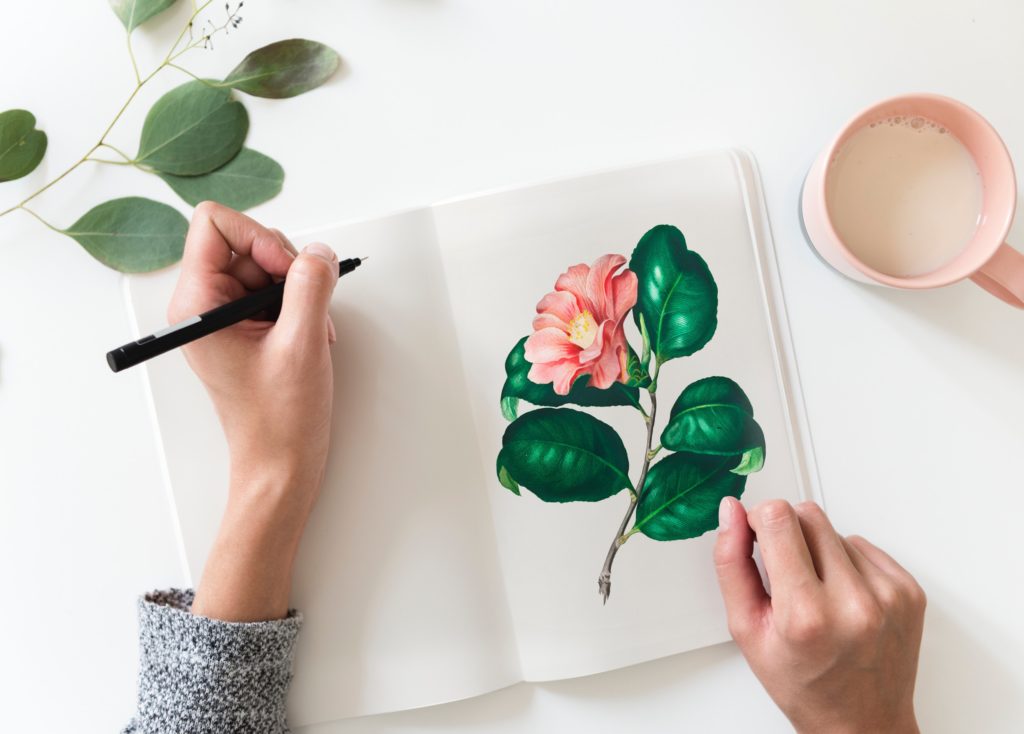 a woman drawing flowers in a notebook