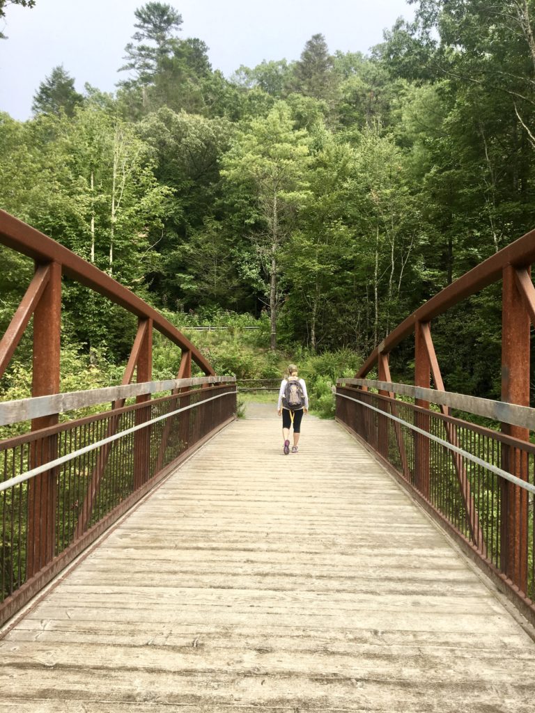 Merry Lerner walking over a bridge by Hooker Falls near Asheville North Carolina